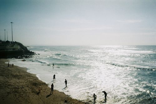 Free People enjoying a sunny day at the beach in Parede, Lisbon with waves crashing on the shore. Stock Photo