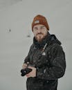 Man with in outerwear with photo camera in snowy terrain