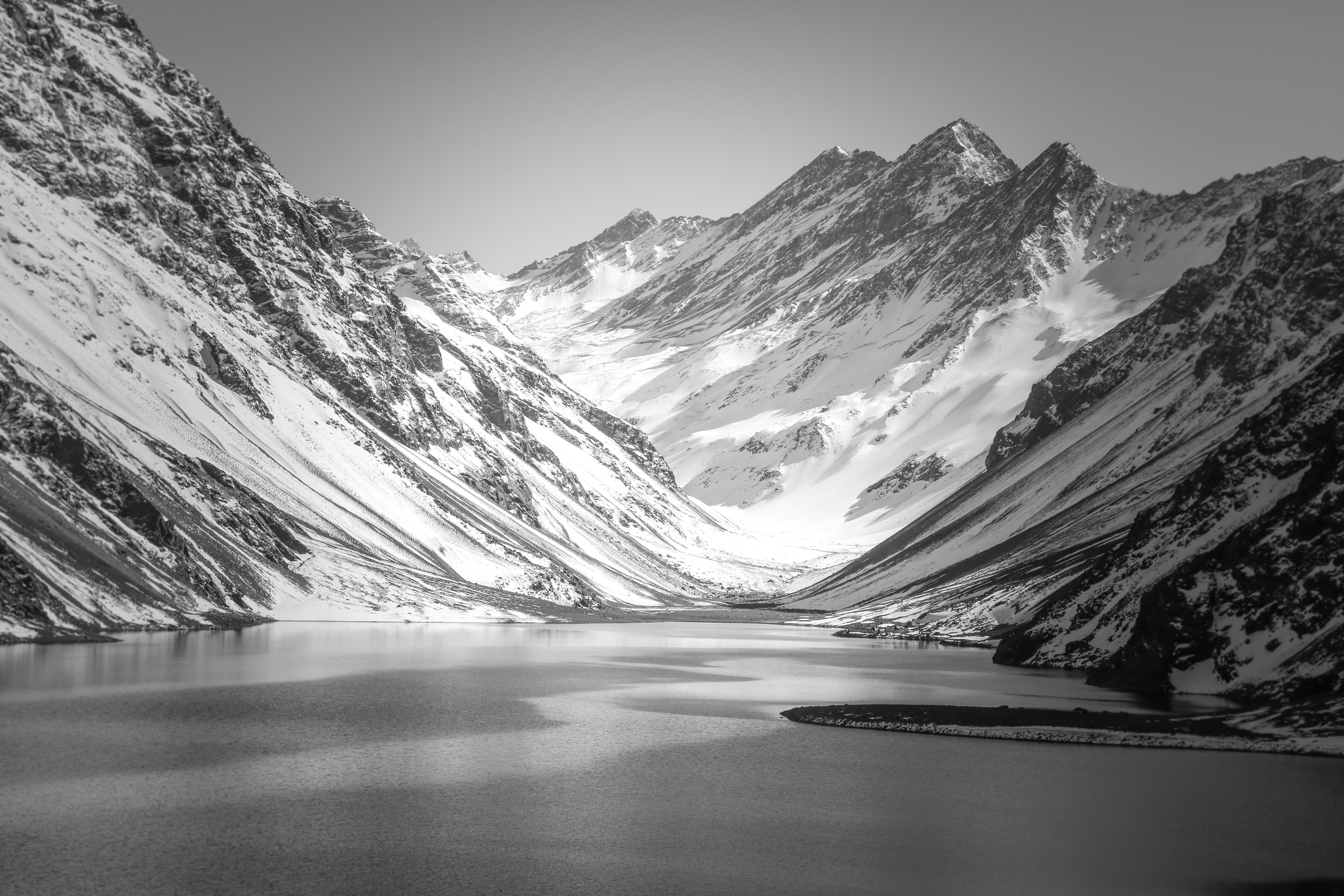 A still mountain lake below steep snow-covered Andean walls with no buildings in sight
