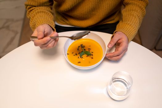 A warm bowl of pumpkin soup garnished and ready to enjoy indoors.