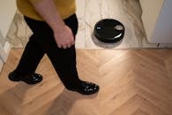 Person Walking Near a Robotic Vacuum Cleaner on Marble Floor