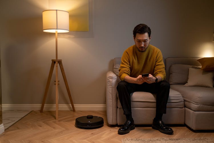 Man Sitting On Sofa While Holding A Cellphone