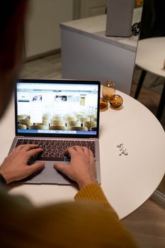 Close-up of hands typing on laptop with AirPods on a table, creating a cozy work environment.