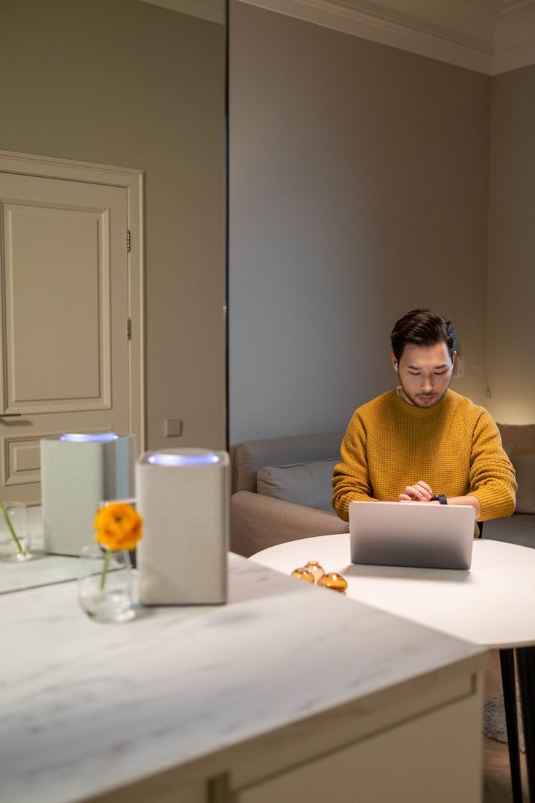 Man In Yellow Sweater Sitting In Front Of A Laptop 