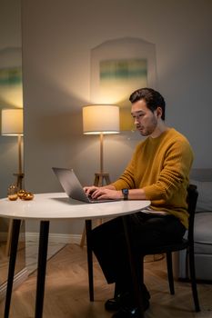 Asian man working on laptop at home in a stylish living room with modern interior design.