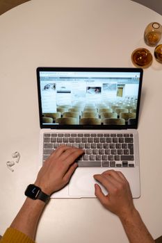 Freelancer working on a laptop with a smartwatch and earphones on a table, seen from above.