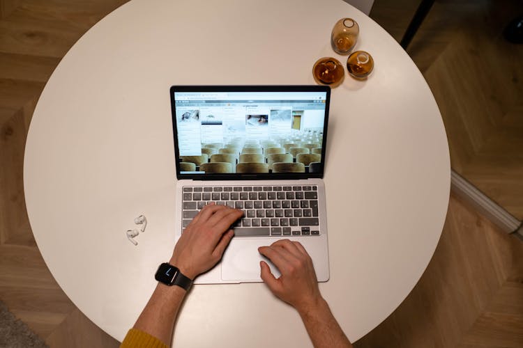 Person Using A Black And Silver Laptop On The Table