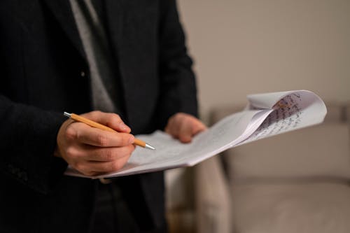 Free A Person in Black Jacket Holding Pen and Stapled Papers
 Stock Photo