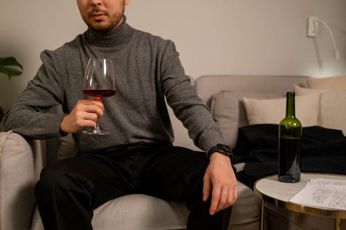 Man in a Gray Turtleneck Holding a Glass of Red Wine
