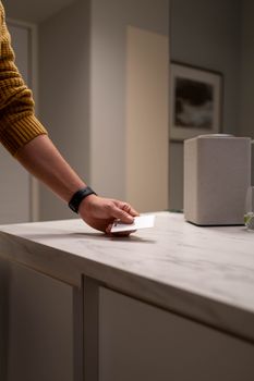 A person wearing a sweater and watch holds a card on a marble countertop.