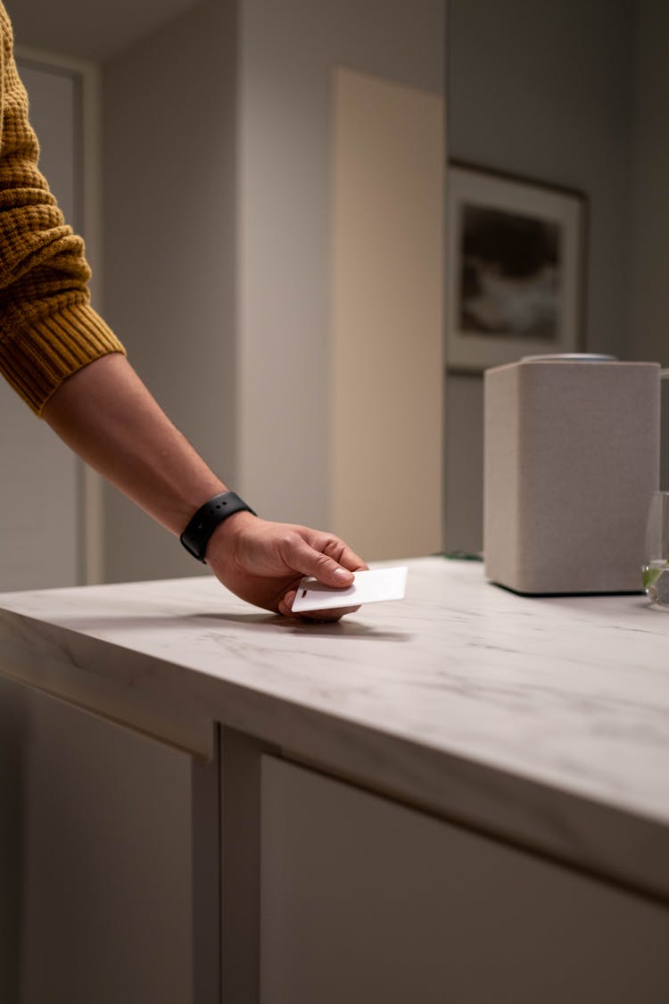 A Person Beside A Counter Holding A Card