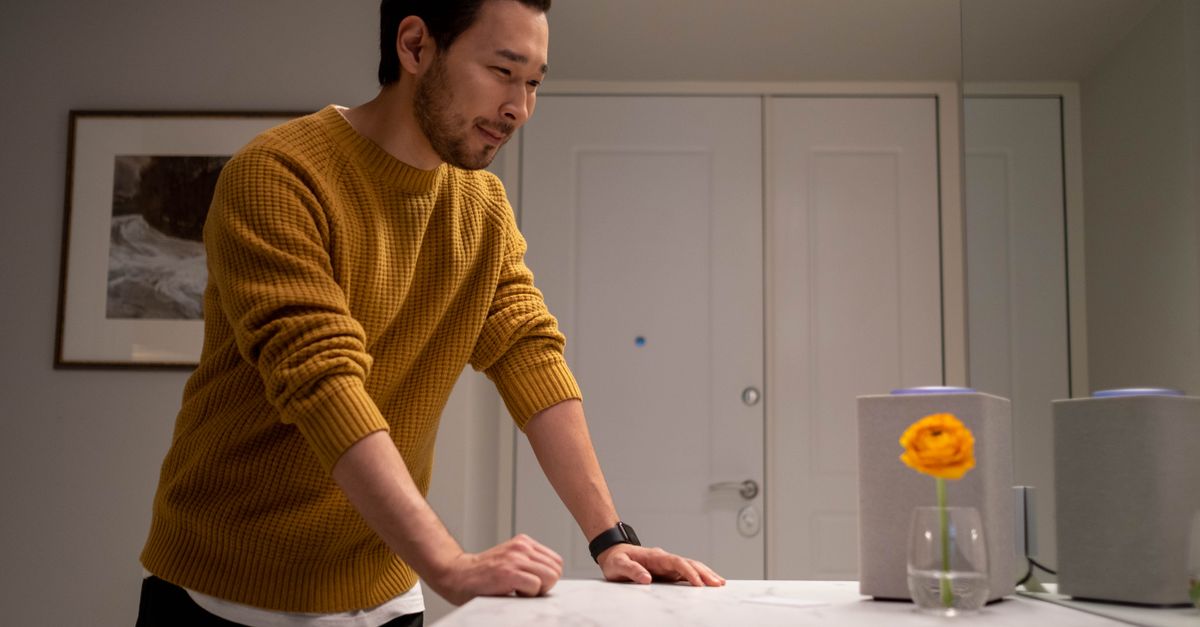 A person looking suspiciously at a smart speaker in a living room