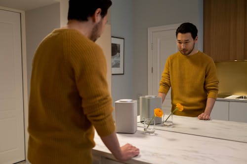 Man in a Mustard Sweater Standing in Front of a Mirror