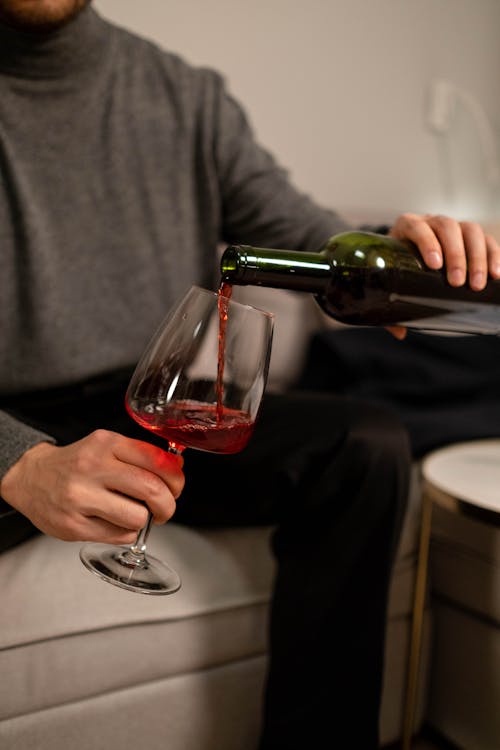 Free Close-Up Photo of a Person's Hands Pouring Red Wine on a Wine Glass Stock Photo