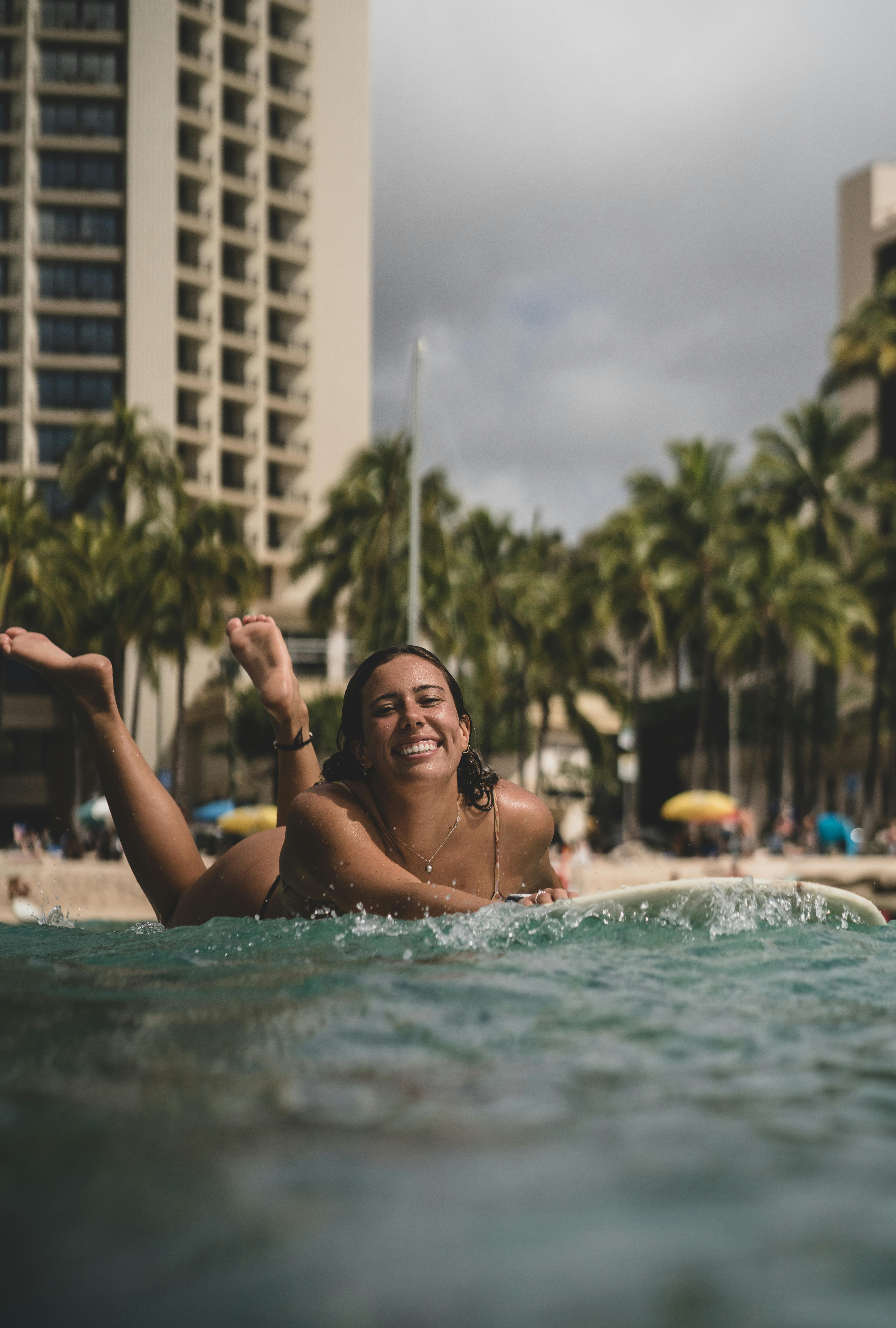 joyful woman lying on surfboard on seawater