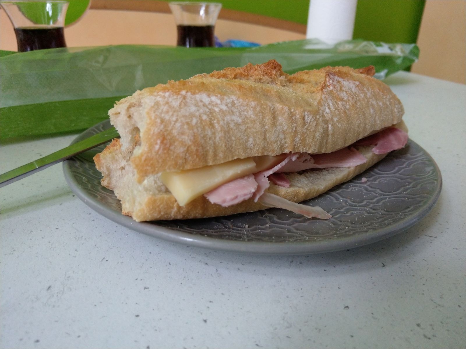 Sandwich baguette jambon-fromage sur une assiette en céramique grise