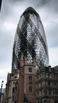 The Gherkin stands tall amidst historic buildings in London's urban landscape.