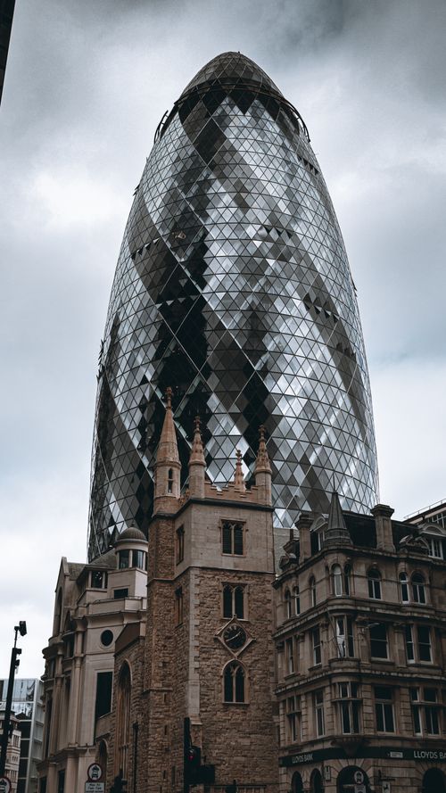 Free The Gherkin stands tall amidst historic buildings in London's urban landscape. Stock Photo
