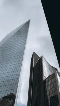 Low angle view of modern skyscrapers in London's financial district with cloudy skies.