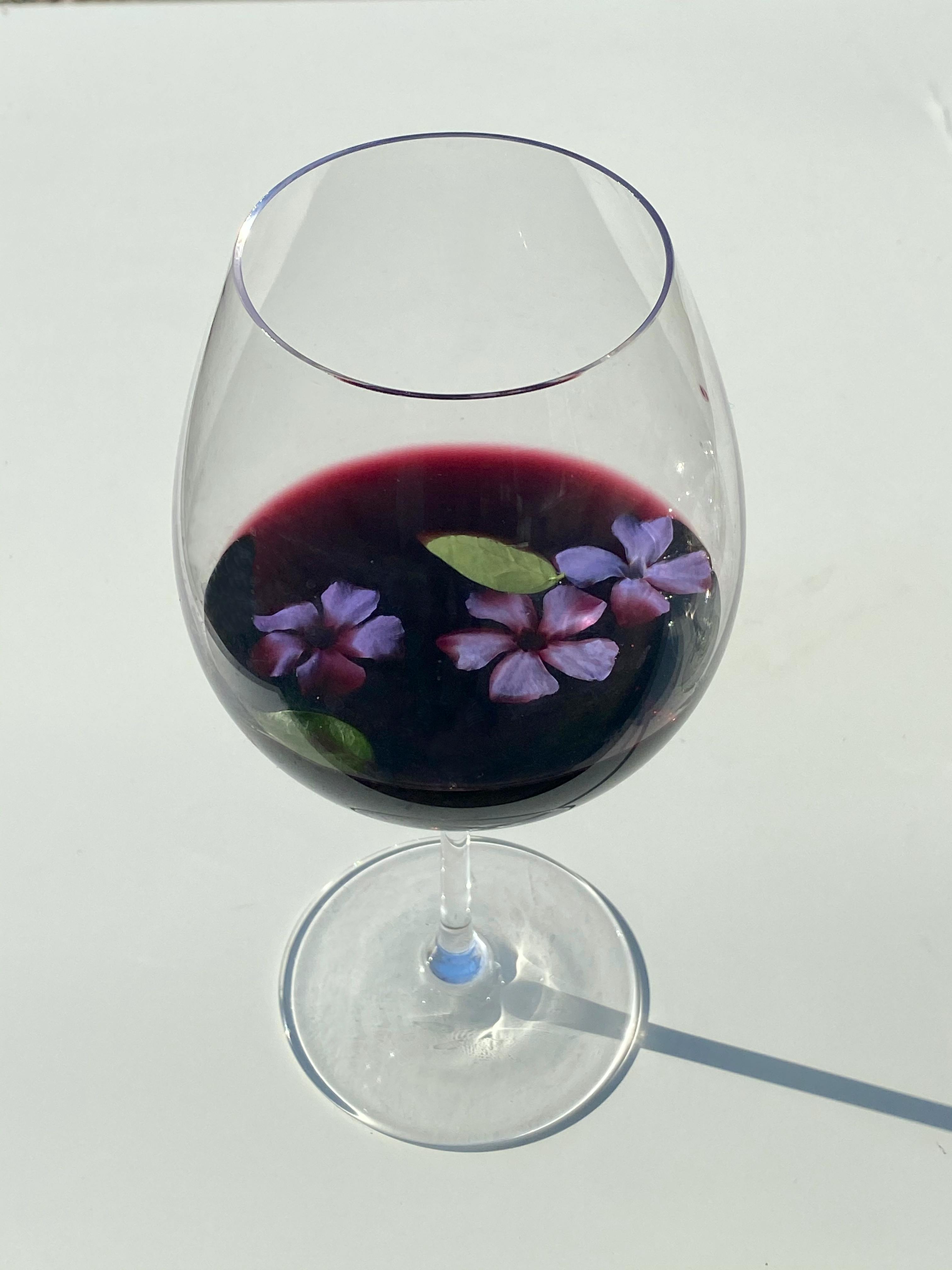 glass of red wine decorated purple flowers