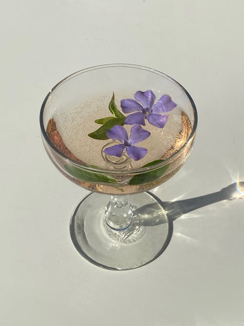 Free Glass with cocktail with flowing flowers of Vinca minor Stock Photo