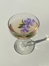 Glass with cocktail with flowing flowers of Vinca minor