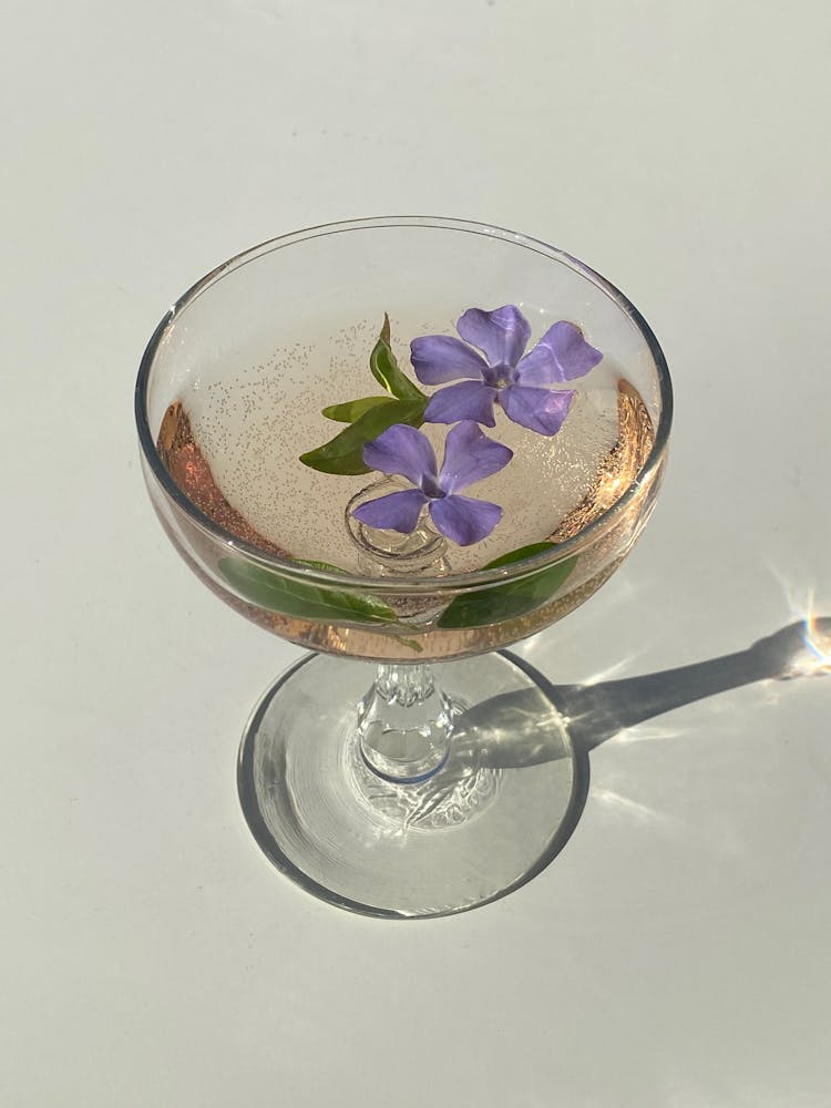 Glass With Cocktail With Flowing Flowers Of Vinca Minor