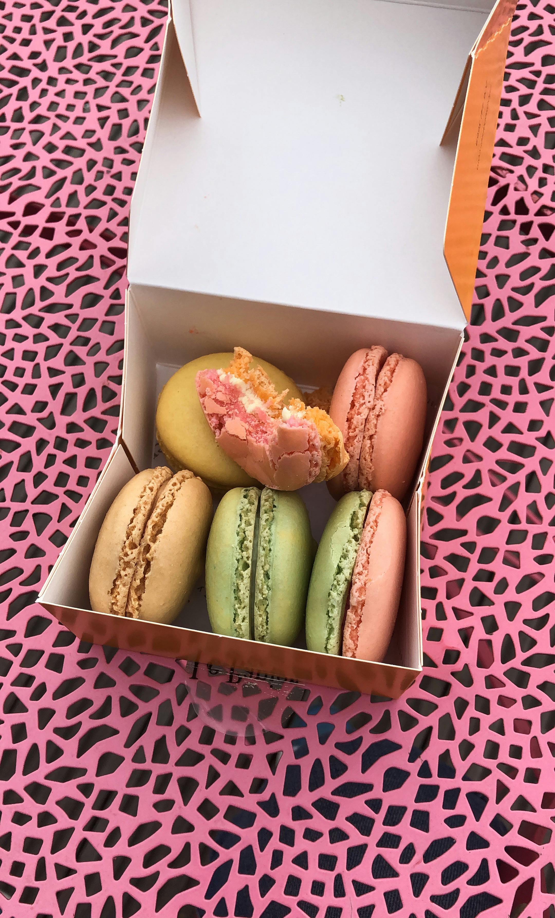 box with colorful macaroons on pink surface