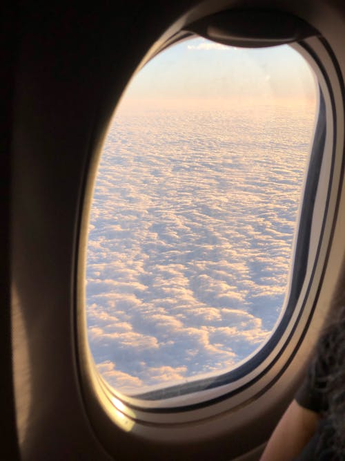 Fluffy clouds though airplane window during flight