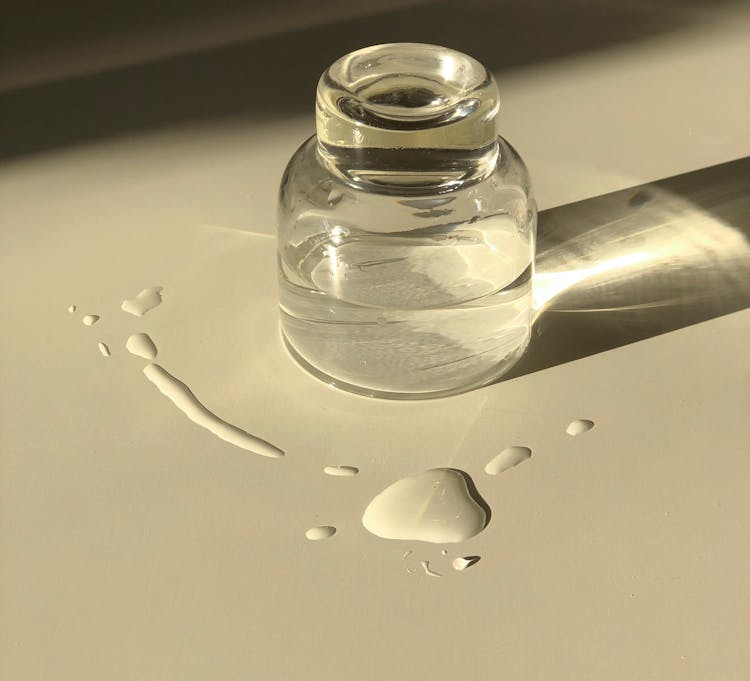 Glass Jar With Transparent Liquid Placed On White Table