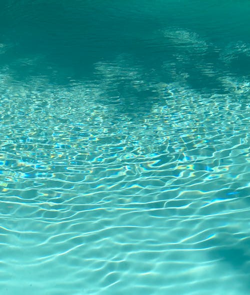 From above of clear blue water of rippling pool on sunny day as abstract background