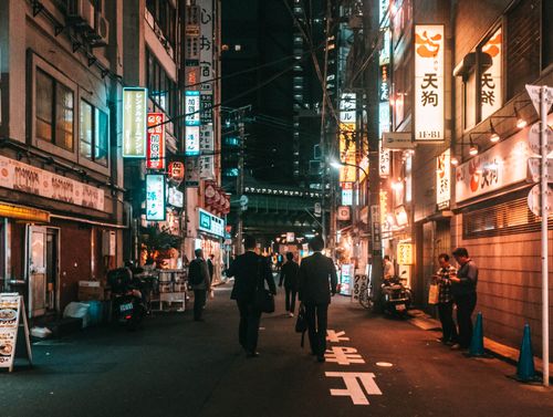 Free Explore Tokyo's vibrant nightlife as people stroll past illuminated signs in the city streets. Stock Photo