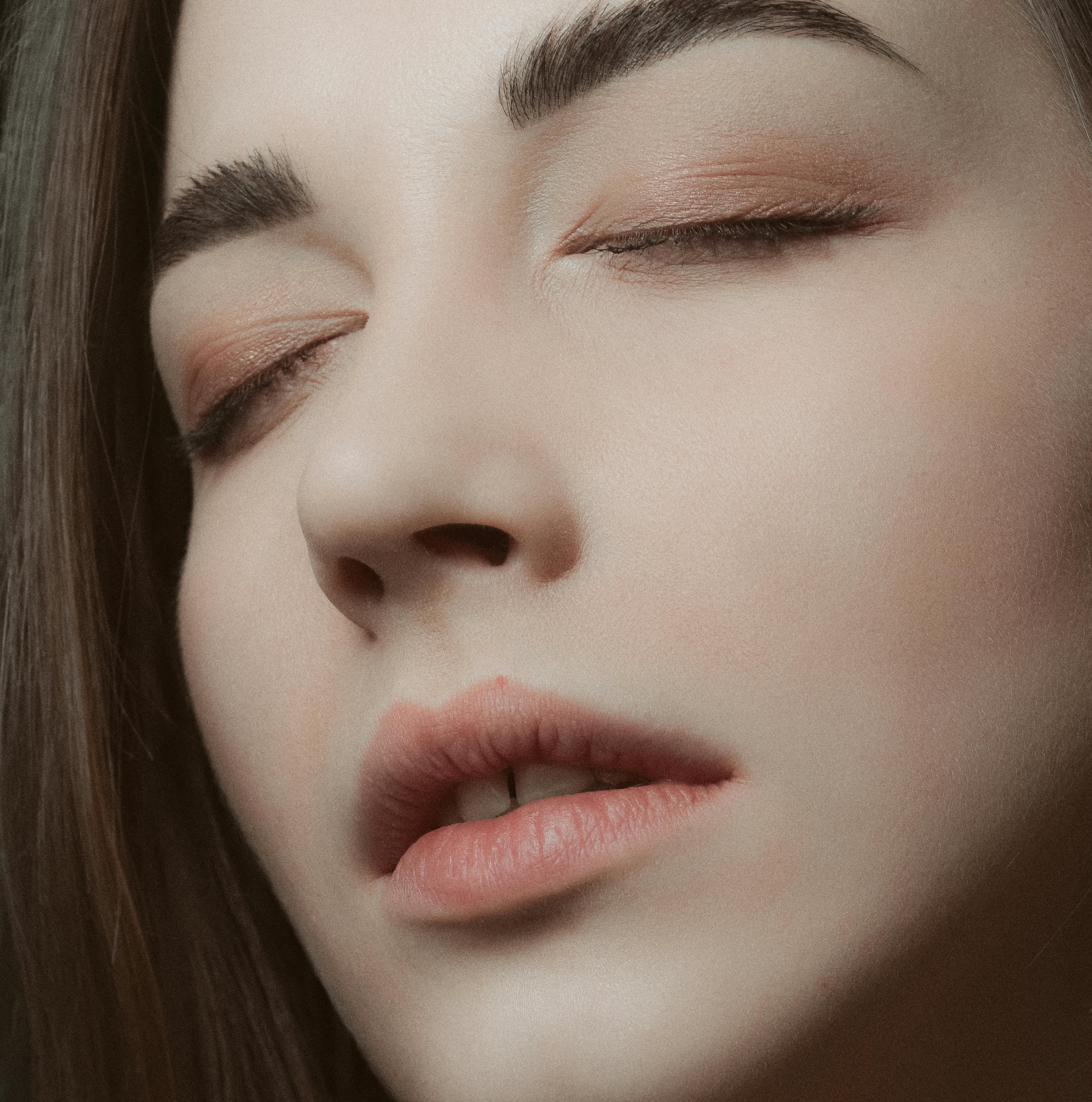 A serene close-up portrait of a woman with closed eyes, highlighting natural beauty and subtle makeu