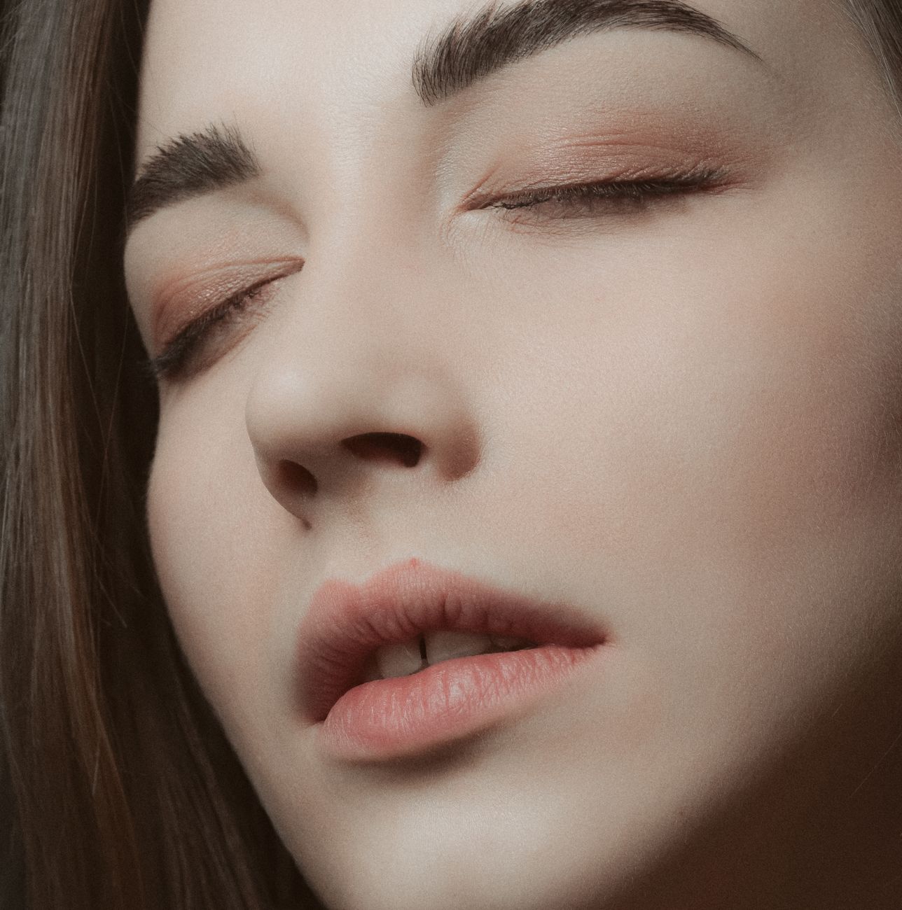 A serene close-up portrait of a woman with closed eyes, highlighting natural beauty and subtle makeup.