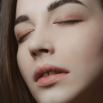 A serene close-up portrait of a woman with closed eyes, highlighting natural beauty and subtle makeup.