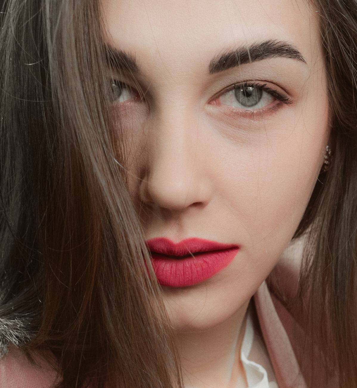 Elegant and captivating close-up shot of a woman with red lips, expressing a confident gaze.