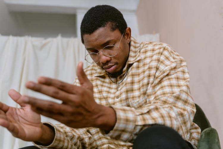 A Man In Brown And White Plaid Shirt Praying