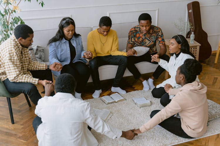 Group Of People Praying In The Living Room