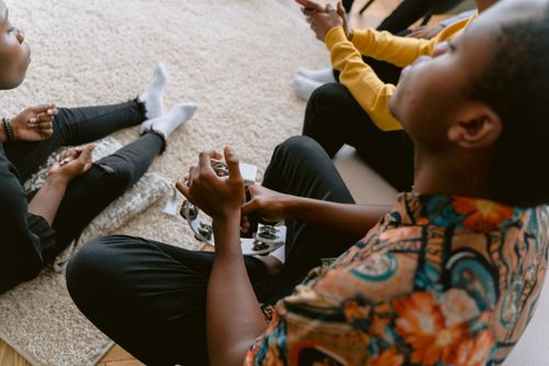 Free People of diverse backgrounds enjoying music with a tambourine. Indoor cozy setting. Stock Photo
