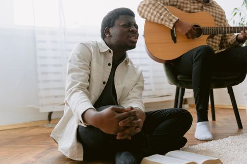 Free A man passionately singing and praying with a guitarist nearby, creating a spiritual atmosphere. Stock Photo