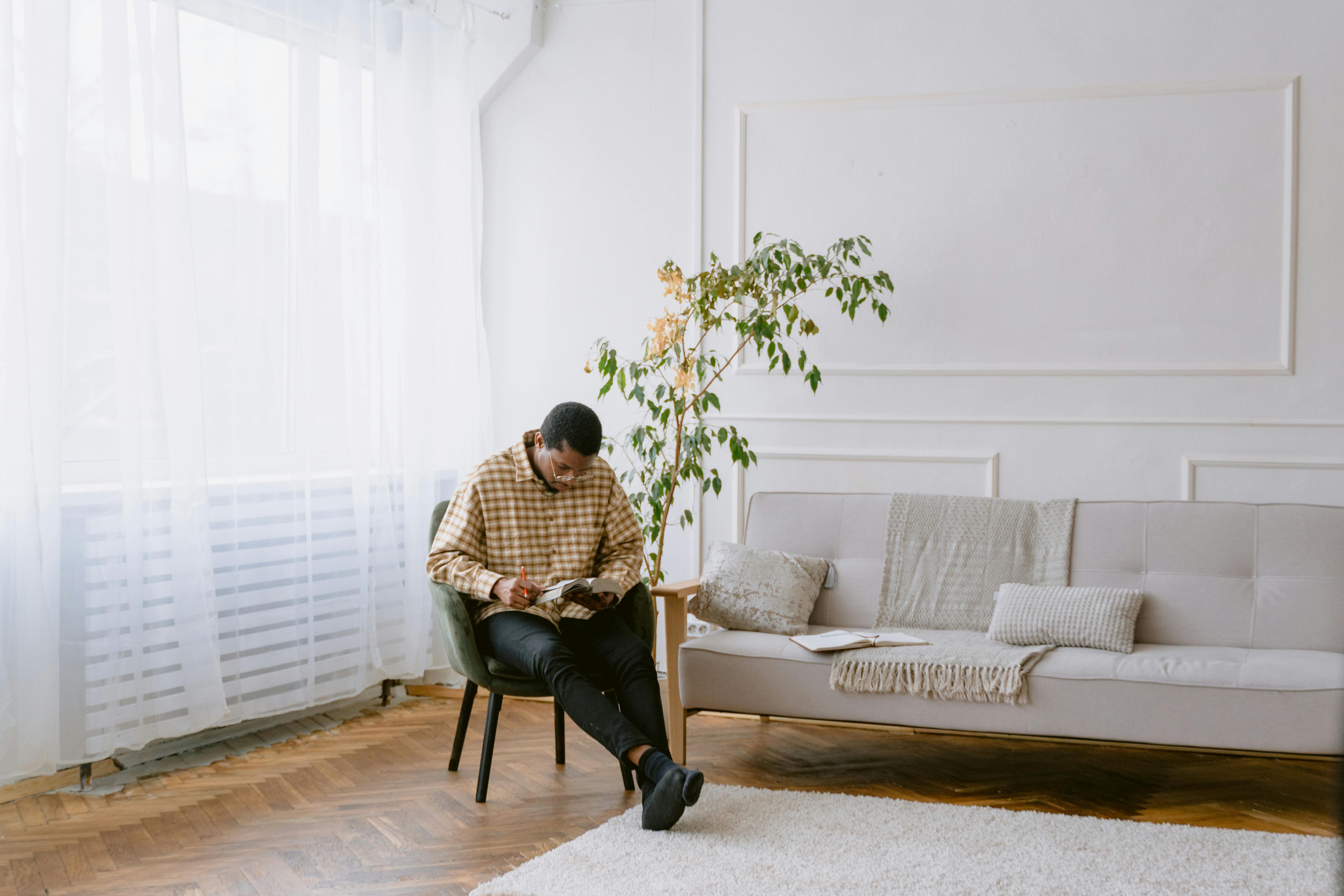 man in white and brown plaid button up shirt reading a bible