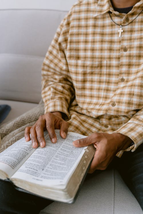 Man in White and Brown Plaid Button Up Shirt Reading Bible 