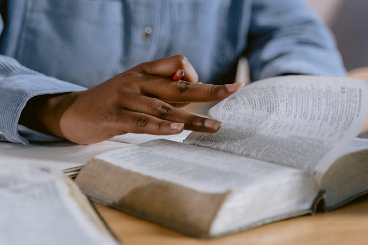 Selective Focus Photo Of A Person's Hand Flipping The Pages Of A Book