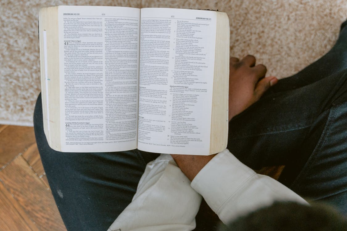 Person in White Long Sleeve Shirt and Blue Denim Jeans Reading Bible ...