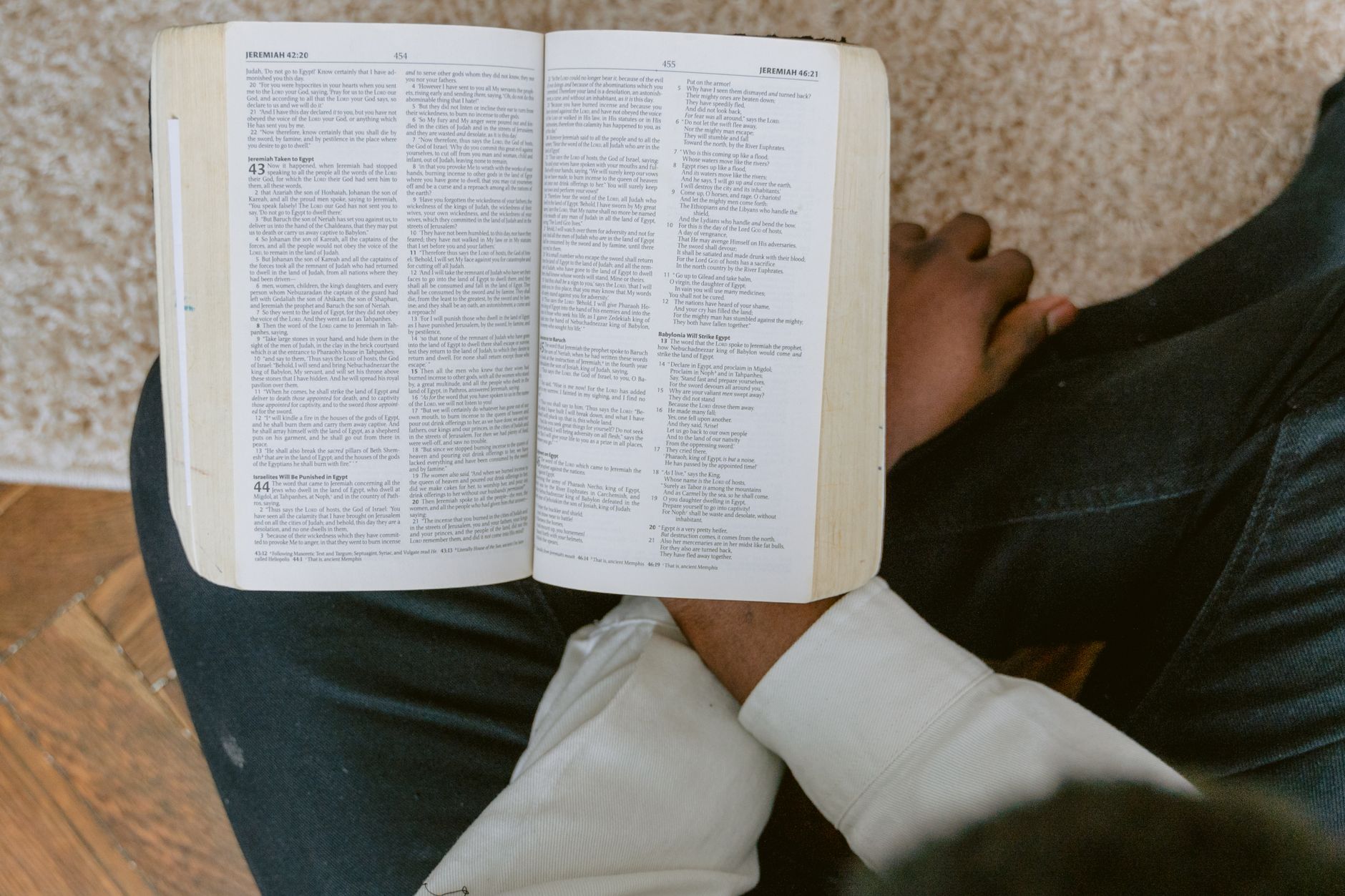 A man is engrossed in reading a Bible while seated indoors.