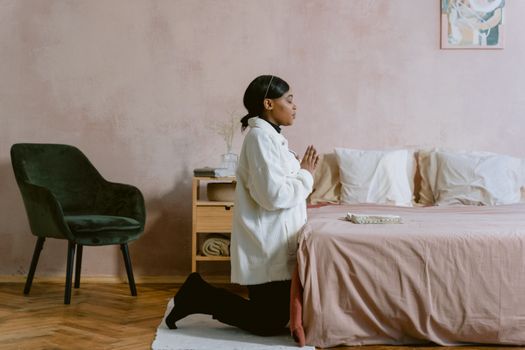 Woman in White Jacket Kneeling While Praying 