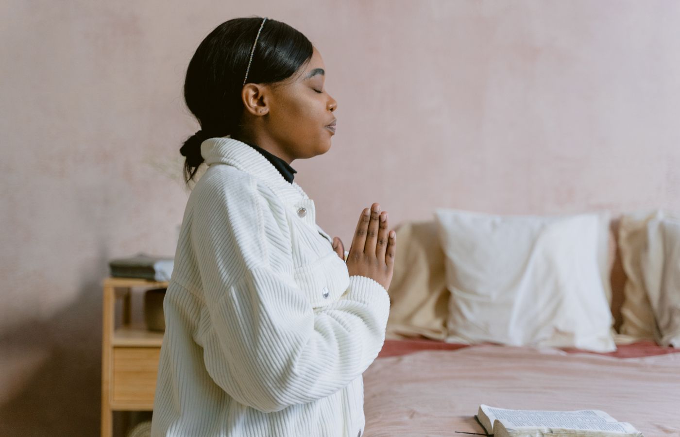 A serene image of a woman with closed eyes in prayer, capturing a moment of spiritual reflection indoors.