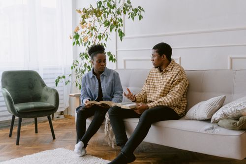Free Two adults engaging in a thoughtful conversation in a cozy living room setting. Stock Photo