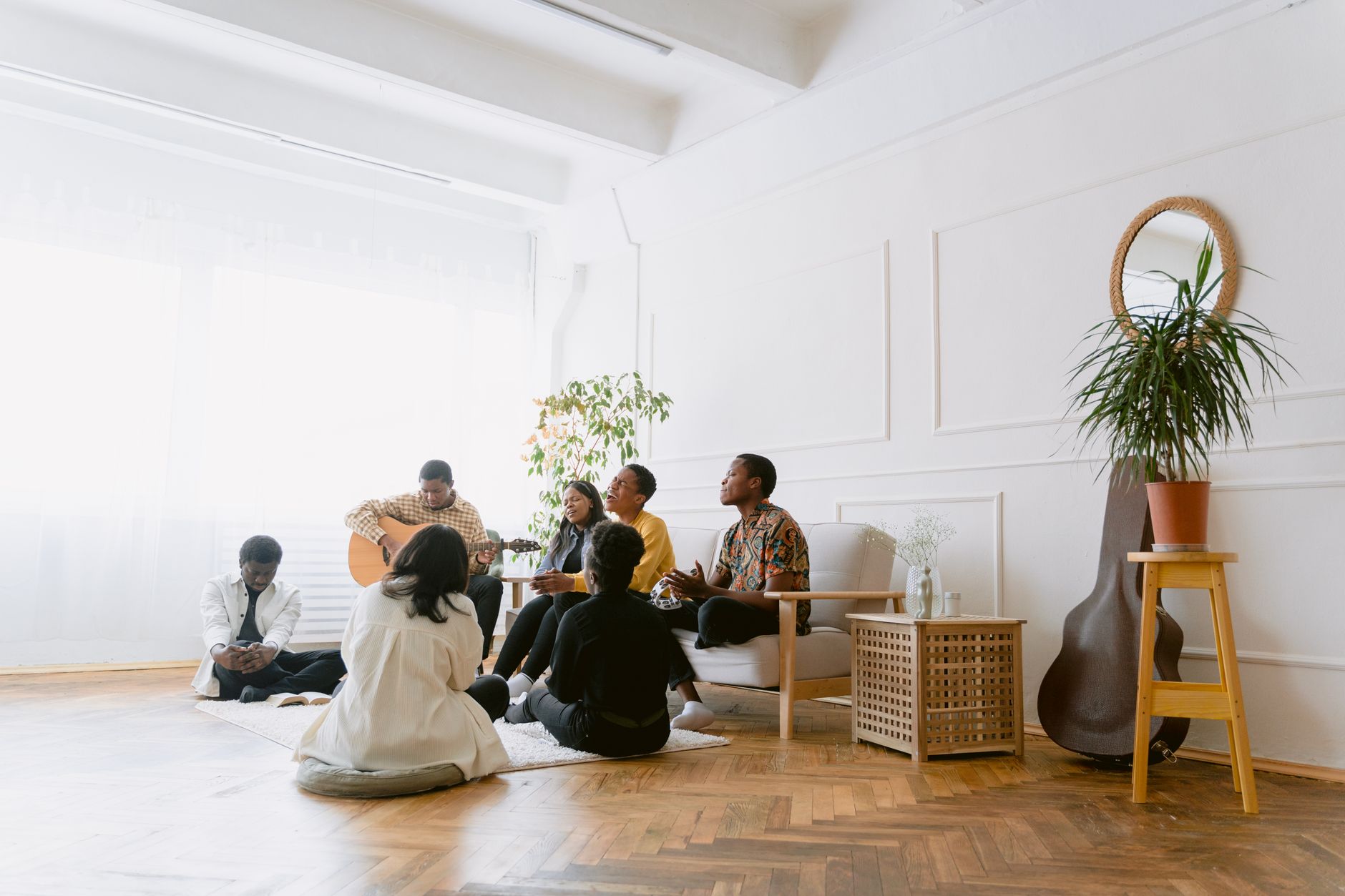 A small group seated in a circle in a bright room with wooden floors, the shape most retreat sessions take