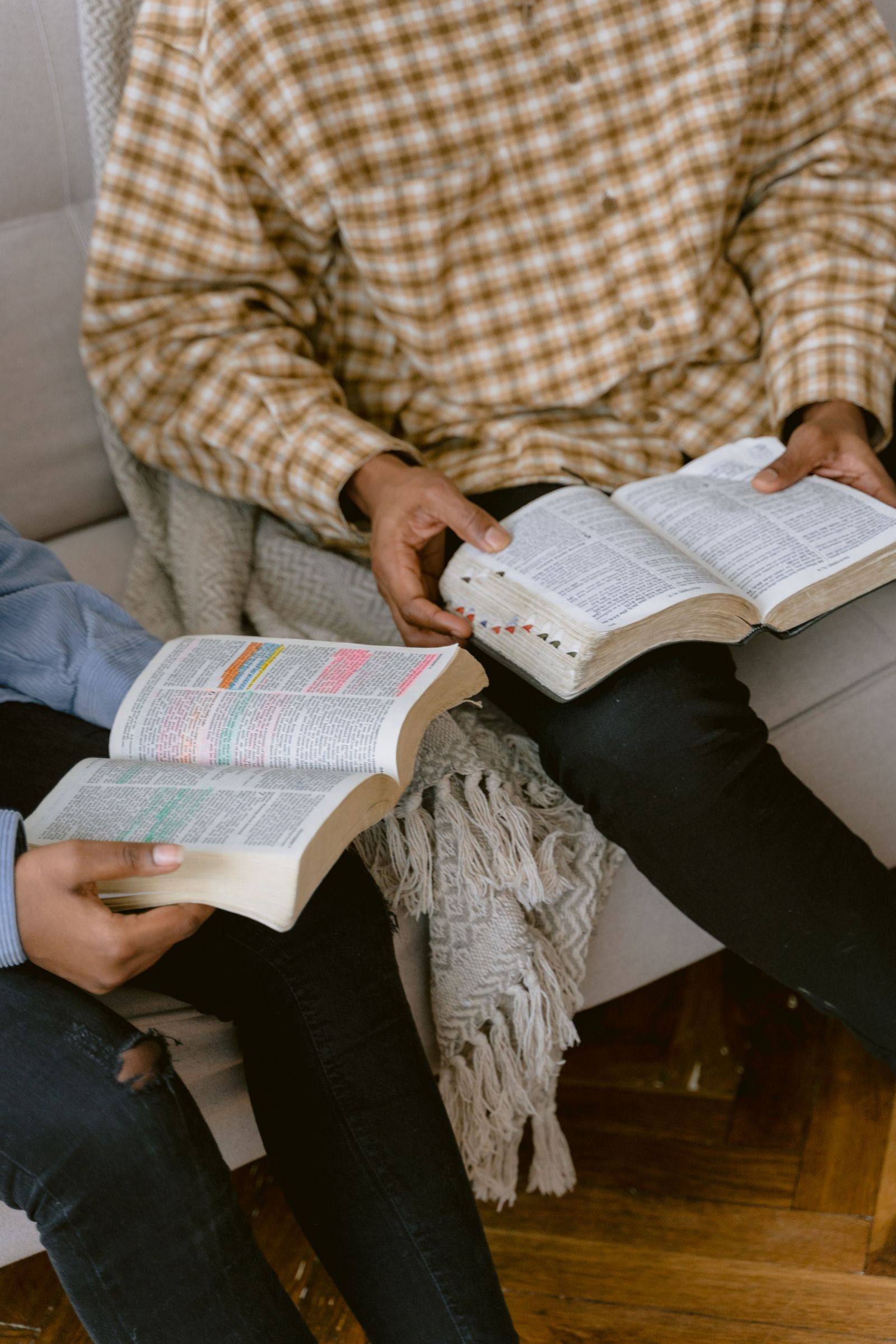 Two adults reading and discussing a Bible on a sofa